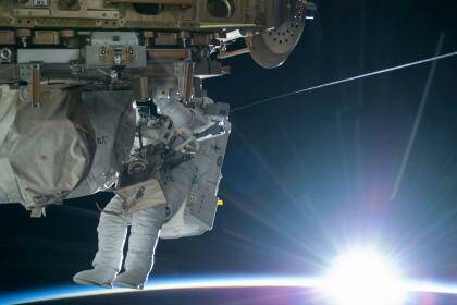 NASA astronaut Terry Virts is seen working to complete a cable routing task while the sun begins to peak over the Earth's horizon on the International Space Station. Photo: NASA