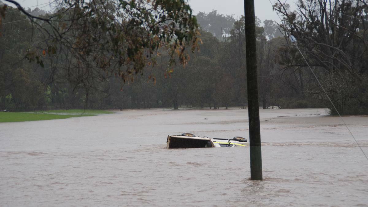 A ute lies submerged in the Thomson Brook flood, in what is normally an access way last month.