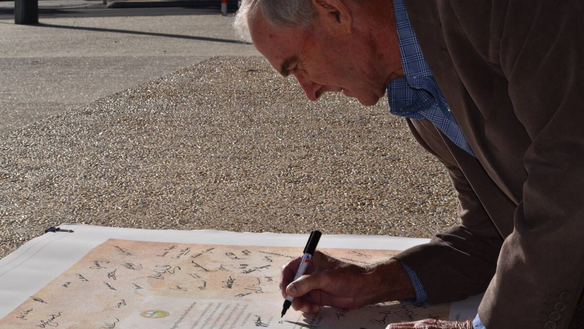 Shire president Michael Smart signing his name to the welcome banner.