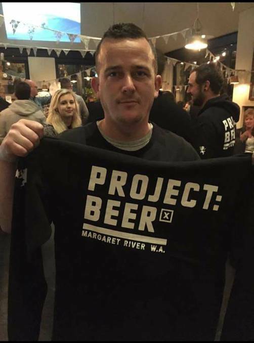 Michael Cook posing with a jumper he won in Margaret River before frauds began. The photo was spread across social media. 