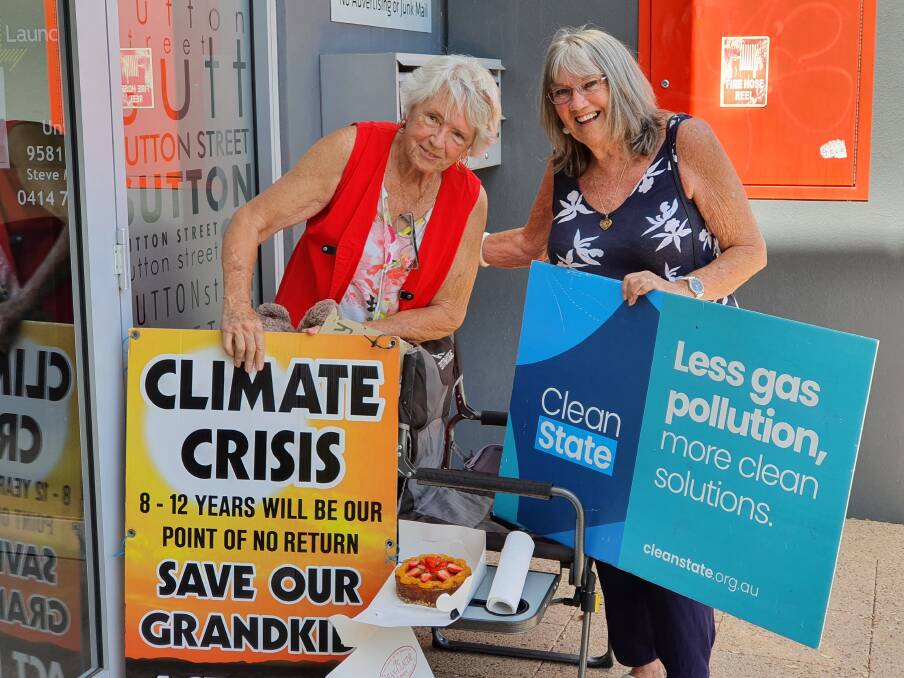 Fridays for Future: Kathie Schmah and Anne Hanson holding placards at their 100th climate change vigil. Photo: Supplied.