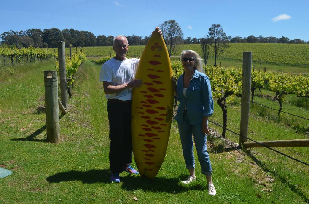 Dunsborough retiree Jim King and Robyn Rigg with the surfboard at Aravina Estate. Image supplied courtesy of Thea McDonald-Lee.