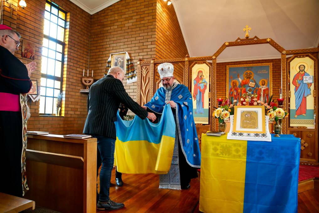 Father Simon Ckuj presents a Ukrainian flag to Wollongong Lord Mayor Gordon Bradbery. Picture: Anna Warr.