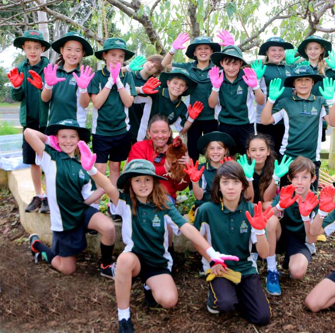 Hands up: Bunnings Activities Organiser Amber Sullivan surrounded by some of the Y5 MRPS Kitchen Garden students, and one chook (also part of the program). Photo: Terri Sharpe.