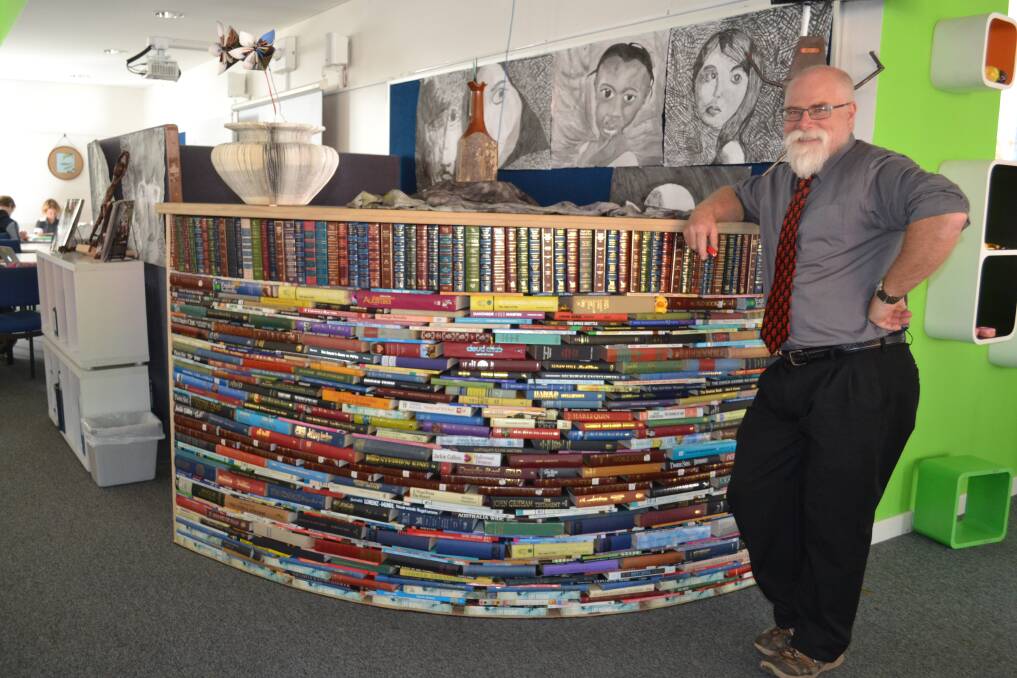 Creative recycling: High school teacher Martin Keen with his newly installed shelf made of books. The paper flowers on the shelf were created by students Stephanie Dowe and Alissa Stammers-Smith.